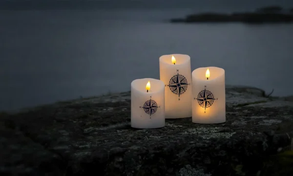 dekorio-hero-v2-kubelys Bilde av tre Kubelys i mørket med kompass merker og en fjernkontroll til å styre de. Dekorio i samarbeid med UndrumDesign i laging av nettside.